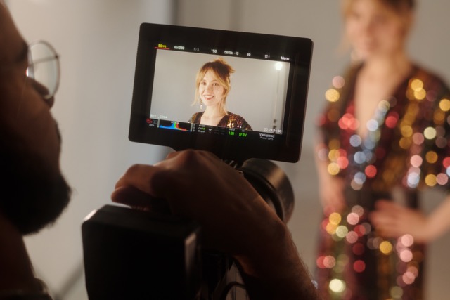 Closeup of filming process with camera monitor showing woman on screen during video shoot in production studio